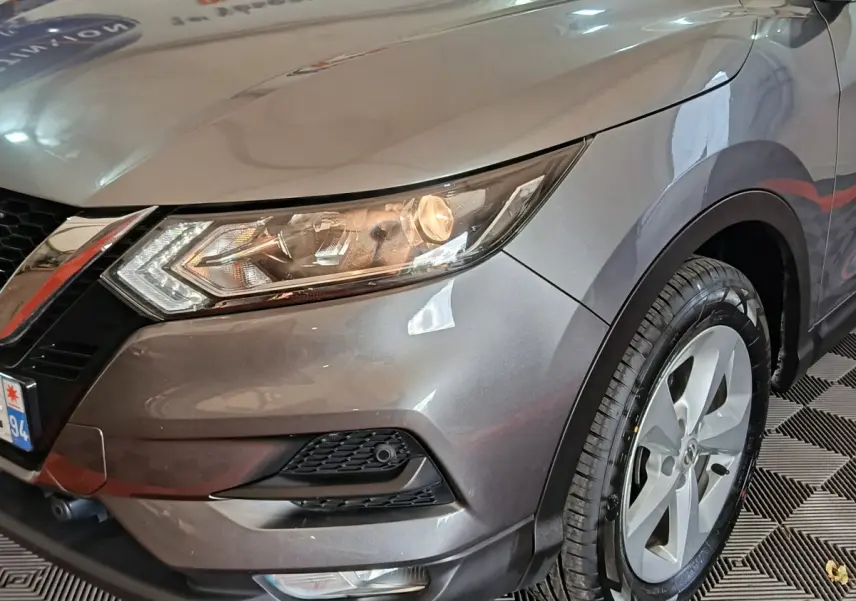 Gros plan sur l'avant droit gris clair du Nissan Qashqai 2019, mettant en valeur son phare et sa roue alliage.