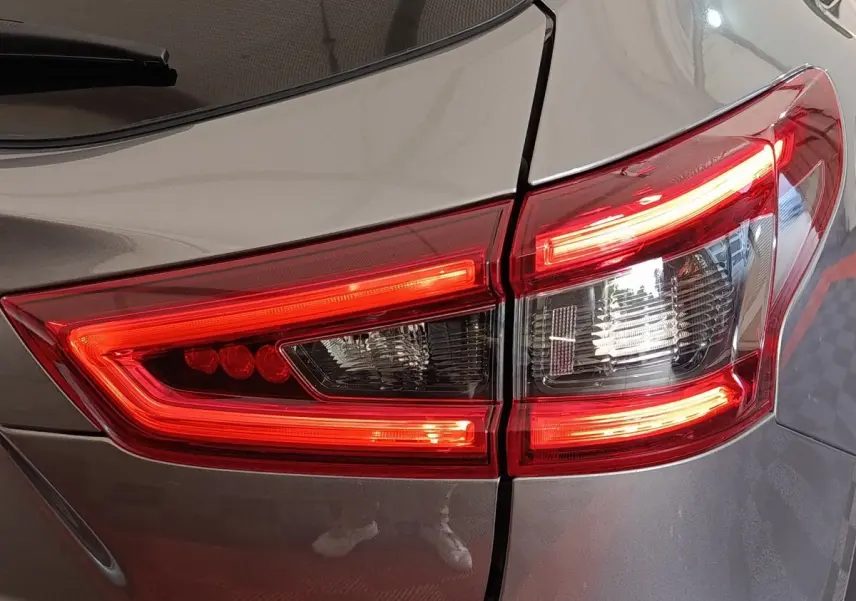 Gros plan sur le feu arrière droit rouge et blanc d’un Nissan Qashqai gris clair 2019.