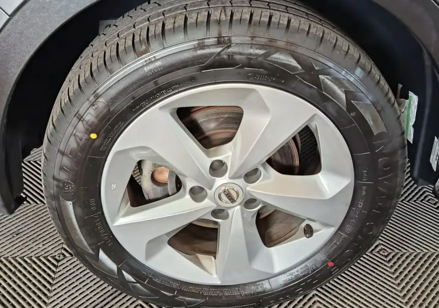 Gros plan sur la roue avant droite du Nissan Qashqai gris clair, jante alliage à cinq branches.