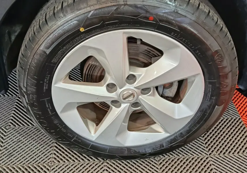 Gros plan sur la roue avant droite du Nissan Qashqai gris clair, jante alliage à cinq branches.