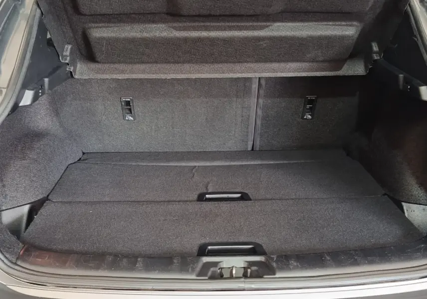 Coffre ouvert du Nissan Qashqai gris clair 2019, vue arrière montrant l'espace de chargement avec tablette de séparation.