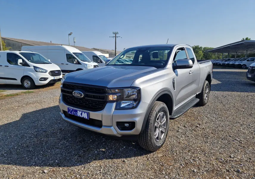 Ford Ranger Super Cabine gris iconic en 3/4 avant droit, avec calandre noire et plaque Zero KM visible.