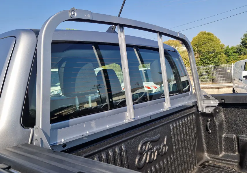Ford Ranger Super Cabine gris iconic vu de profil côté gauche sur un terrain gravillonné avec maison en arrière-plan.