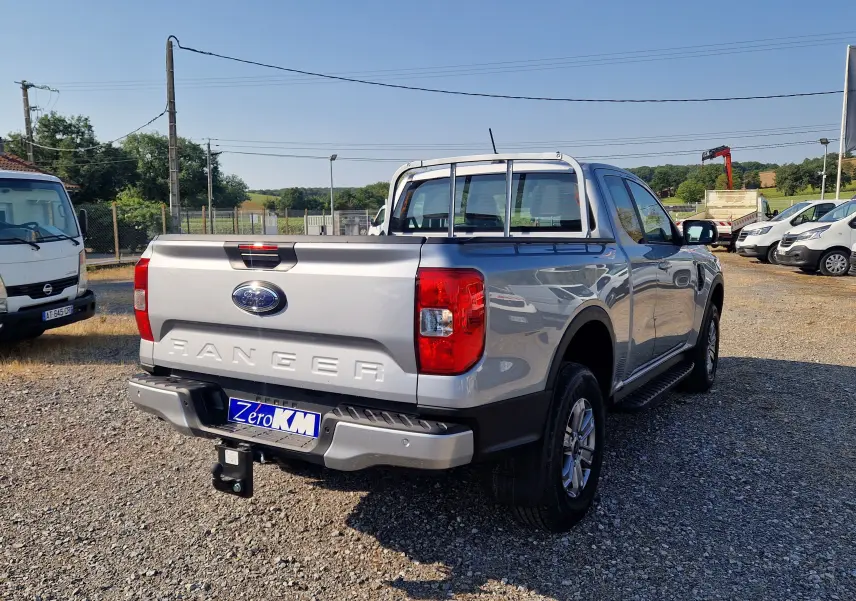Ford Ranger Super Cabine gris Iconic vu en 3/4 arrière droit, avec attelage et barres de protection sur la benne.