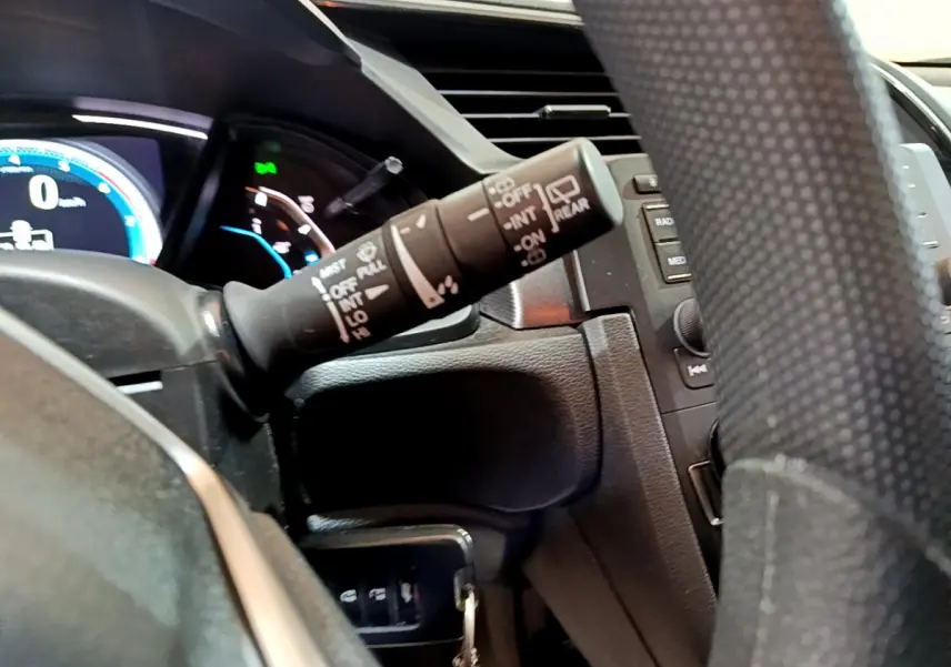 Gros plan sur la commande d’essuie-glace à gauche du volant dans l’habitacle d’une Honda Civic gris foncé 2020.