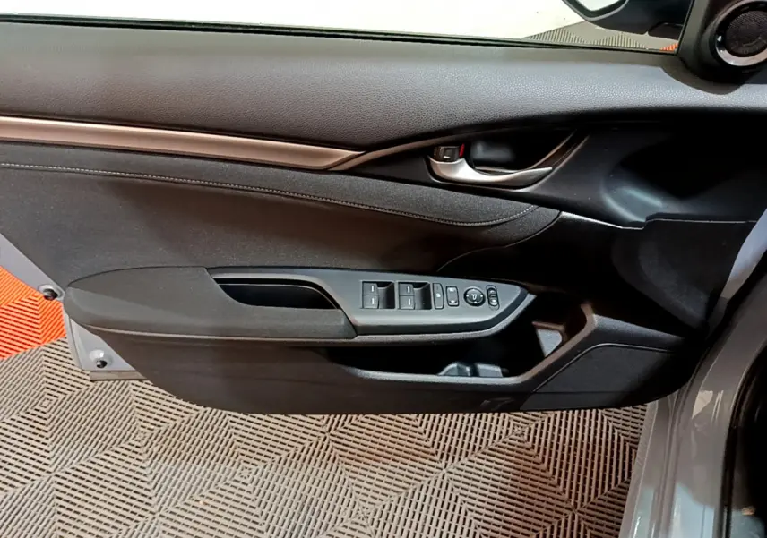 Vue intérieure côté gauche de la porte avant d'une Honda Civic 1.0 i-VTEC Exclusive gris foncé avec commandes des vitres et rétroviseurs.