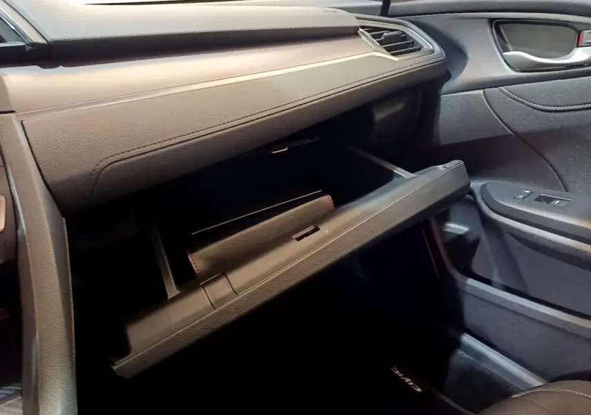 Vue intérieure côté passager de la Honda Civic 1.0 i-VTEC 2020, boîte à gants ouverte et tableau de bord gris foncé.