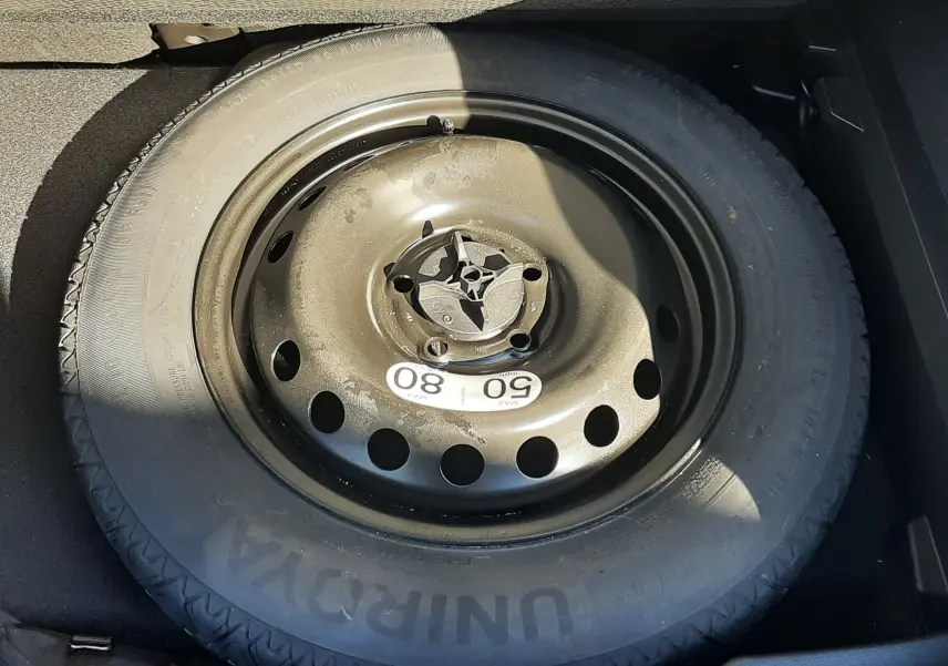 Gros plan sur la roue de secours noire en acier dans le coffre du Renault Captur E-Tech 145ch Intens blanc nacré.