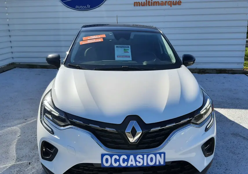 Vue frontale d'un Renault Captur E-Tech blanc nacré avec toit noir, badge Renault et panneau "OCCASION" visible.