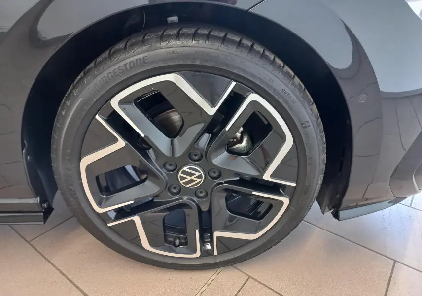 Gros plan sur la roue avant droite d'une Volkswagen Golf 1.5 eTSI R-Line noire avec jante alliage noire et argent.