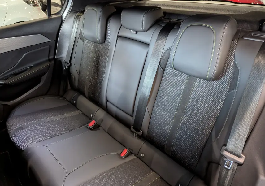 Vue intérieure montrant la banquette arrière en cuir noir avec surpiqûres vertes de la Peugeot 308 GT 2025.