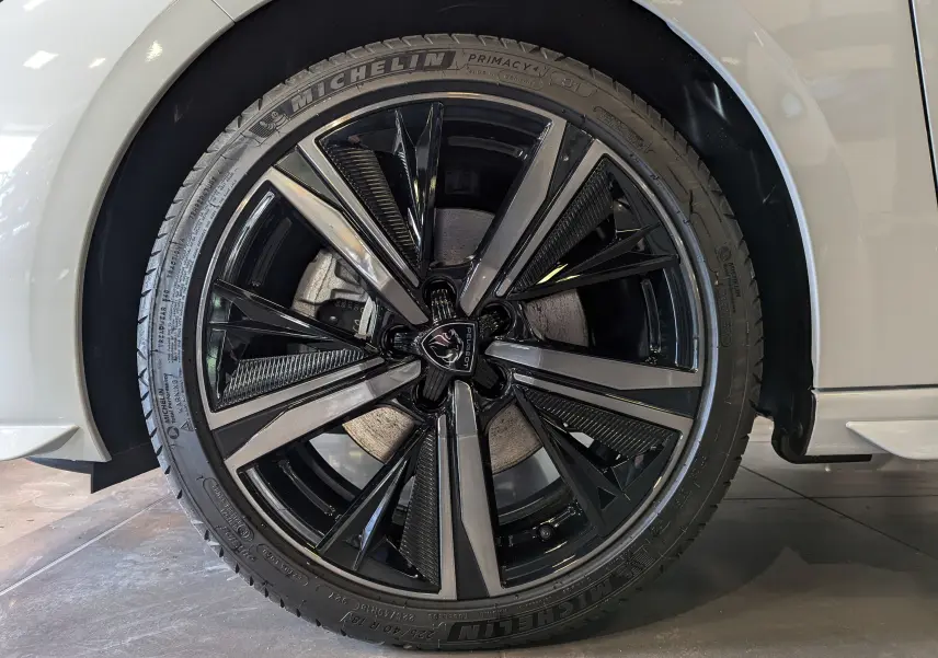 Gros plan sur la roue avant droite d'une Peugeot 308 GT blanche avec jante alliage noire et grise au design moderne.