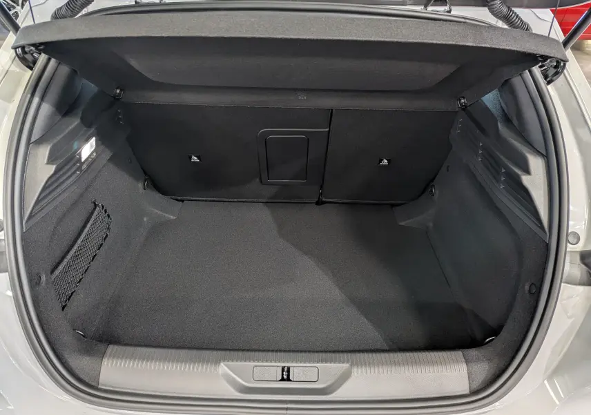 Coffre ouvert de la Peugeot 308 Blanc Okénite, vue de dessus montrant l'espace de chargement vide et les finitions intérieures noires.