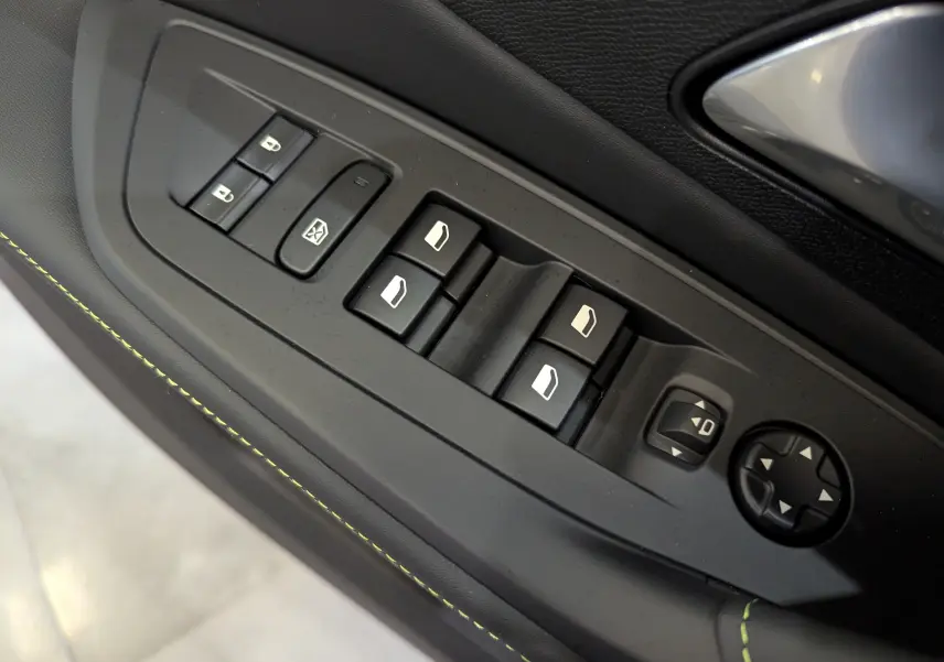 Gros plan sur les commandes de lève-vitres et rétroviseurs côté conducteur de la Peugeot 308 GT blanc Okénite.