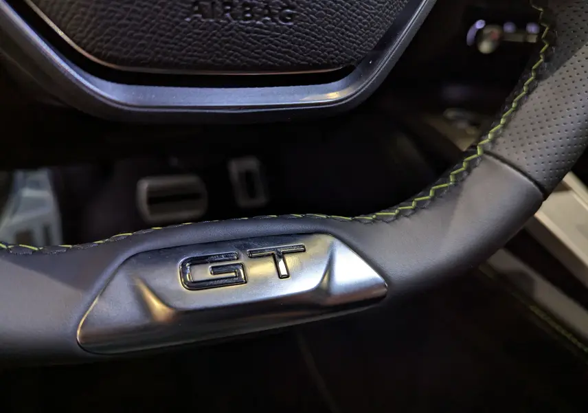 Gros plan sur le volant cuir noir avec surpiqûres vertes et logo GT de la Peugeot 308 BlueHDi 130 CH EAT8 GT.