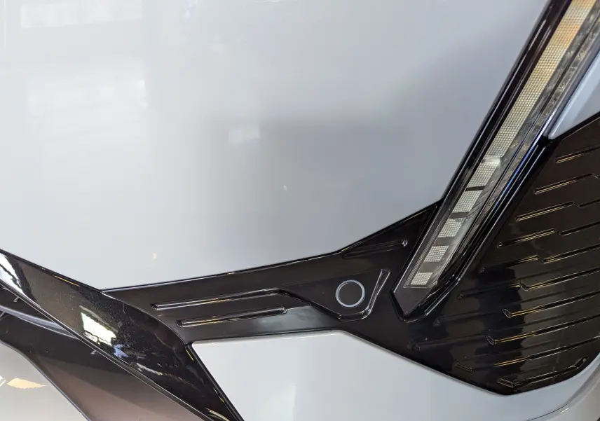 Détail du pare-chocs avant blanc Okénite de la Peugeot 308 GT 2025 avec insert noir et capteur de stationnement.