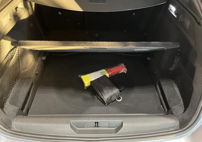 Coffre ouvert d'un Peugeot 308 SW gris clair Metal Artense, montrant le compartiment de rangement avec un triangle de signalisation.