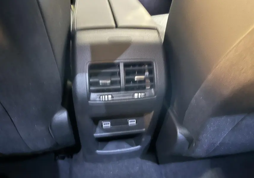 Vue rapprochée des aérateurs arrière et ports USB entre les sièges avant d'une Peugeot 308 SW gris clair 2024.