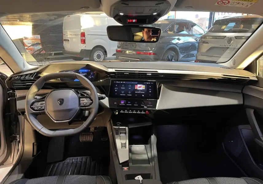 Intérieur avant d'une Peugeot 308 SW 2024 gris clair Metal Artense, tableau de bord moderne avec écran tactile central.