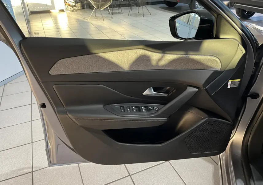 Vue intérieure de la porte côté conducteur de la Peugeot 308 SW 2024 en gris clair Metal Artense avec commandes électriques.