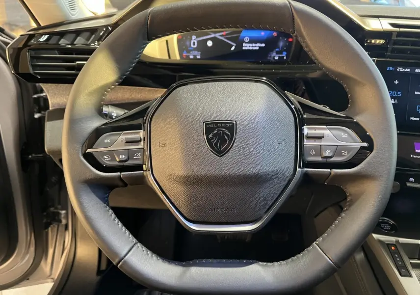 Vue rapprochée du volant cuir noir de la Peugeot 308 SW 2024 avec commandes intégrées et tableau de bord numérique.