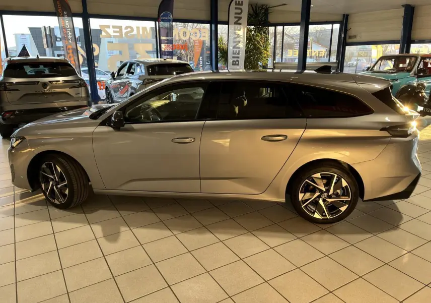 Peugeot 308 SW gris clair métallisé vue de profil côté gauche en intérieur avec jantes alliage distinctives.