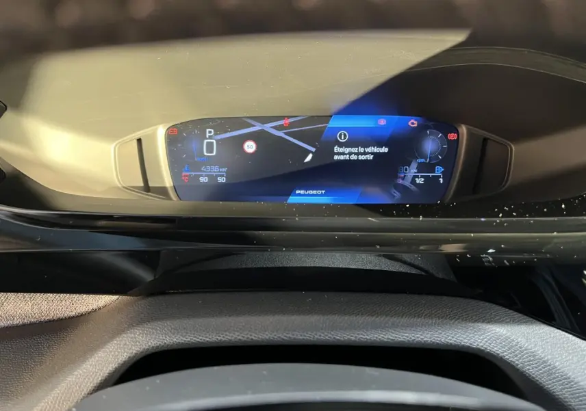 Tableau de bord numérique du Peugeot 308 SW 2024 affichant la navigation et alertes, vue intérieure frontale.