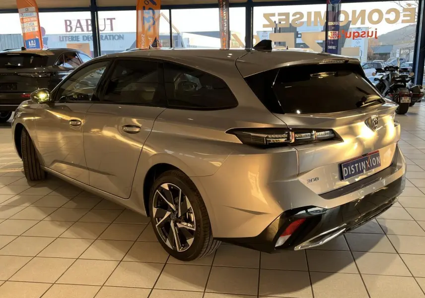Peugeot 308 SW gris clair Metal Artense vue 3/4 arrière droit en showroom avec jantes alliage distinctives.