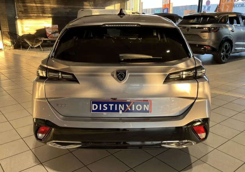 Vue arrière d'un Peugeot 308 SW gris clair Metal Artense avec feux LED et double sortie d'échappement chromée en showroom.