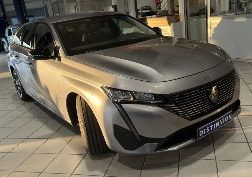 Peugeot 308 SW gris clair Metal Artense en 3/4 avant droit, avec calandre noire et feux LED distinctifs.