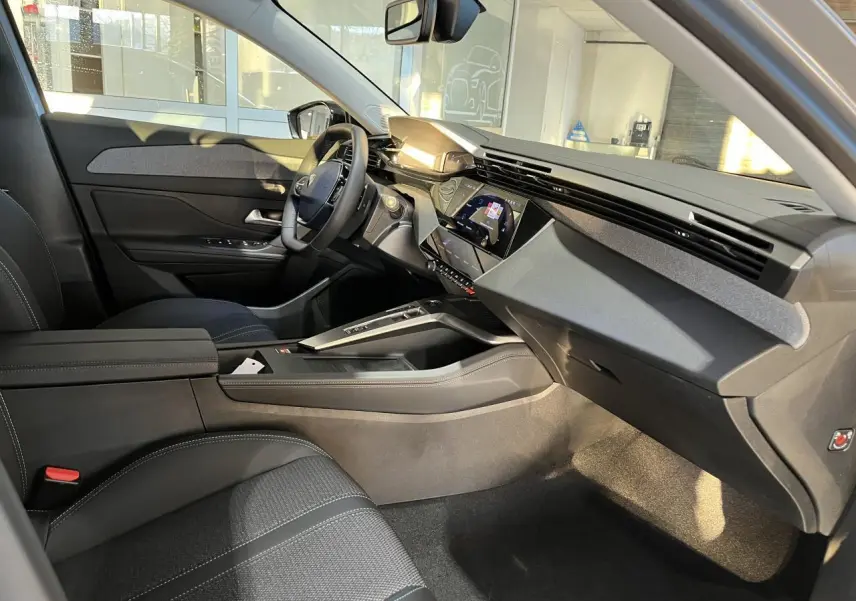 Intérieur côté conducteur de la Peugeot 308 SW 2024, avec tableau de bord moderne et sellerie noire textile.