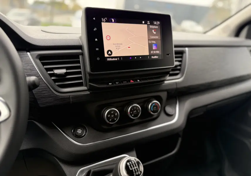 Tableau de bord du Renault Trafic Combi 2025 avec écran tactile, commandes de climatisation et levier de vitesse manuel.