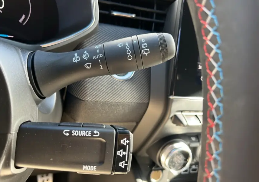 Gros plan sur la commande d’essuie-glace et la commande audio au volant avec surpiqûres tricolores du Renault Clio V E-Tech 145 Esprit Alpine.