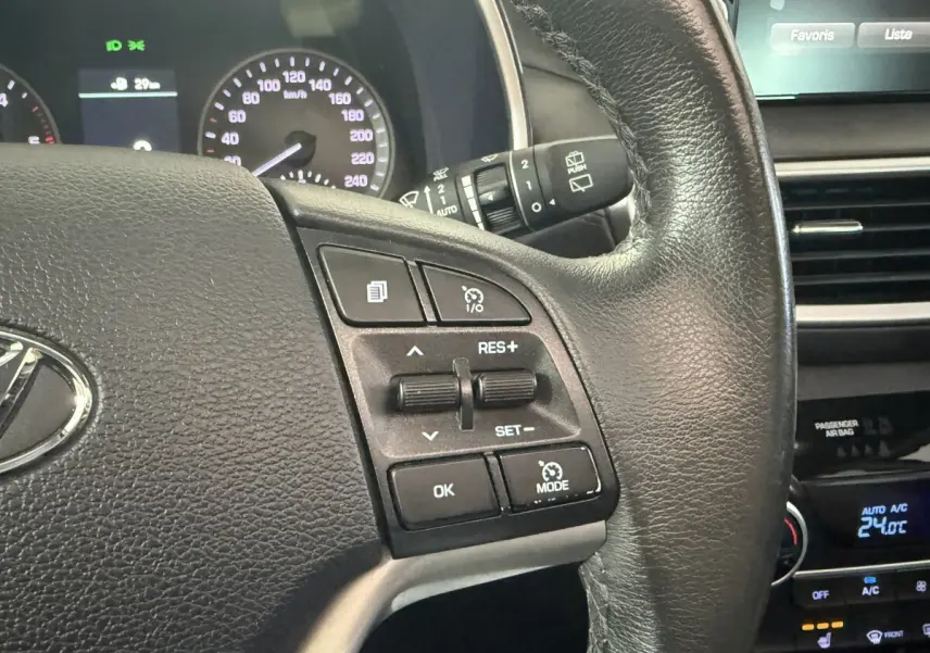 Gros plan sur le volant cuir noir du Hyundai Tucson 2019 avec commandes de régulateur de vitesse et tableau de bord partiel.