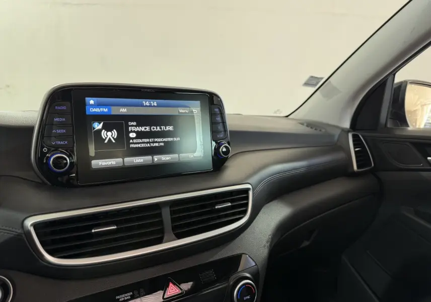 Vue intérieure du tableau de bord du Hyundai Tucson noir 2019, avec écran tactile central affichant une radio.