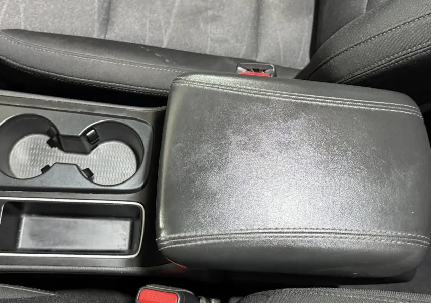 Gros plan sur l'accoudoir central noir en cuir et porte-gobelets du Hyundai Tucson 2019, intérieur sombre.