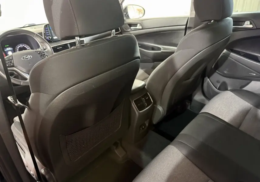 Vue intérieure arrière du Hyundai Tucson 2019 noir, montrant les sièges tissu bicolore et la console centrale avec aérateurs.