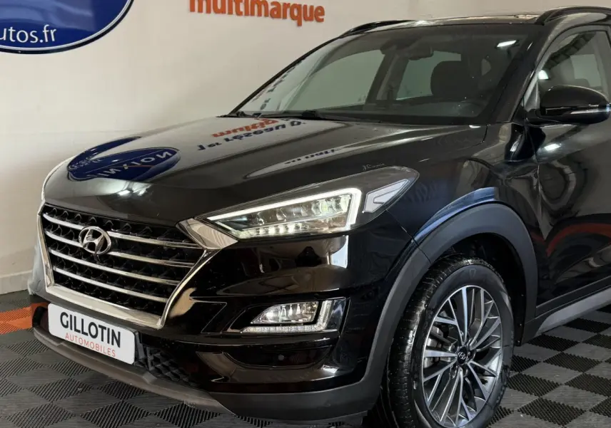 Vue 3/4 avant droit d'un Hyundai Tucson noir 2019 avec calandre chromée et phares LED distinctifs.