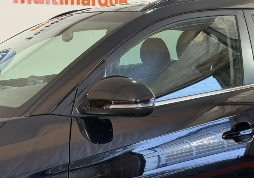 Gros plan sur la porte avant gauche noire d’un Hyundai Tucson 2019, avec rétroviseur et poignée visibles.