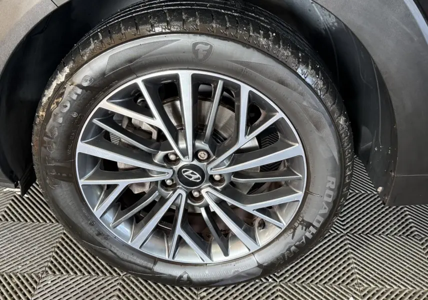 Gros plan sur la roue avant droite noire d’un Hyundai Tucson 1.6 CRDI 136 Premium avec jante alliage multibranches.