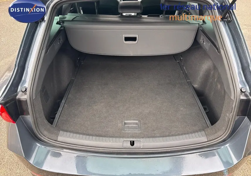 Coffre ouvert d'une CUPRA LEON ST 2024 gris magnétique, vue arrière montrant l'espace de chargement vide et la plage arrière rétractable.