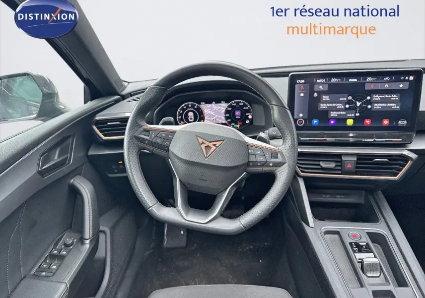 Vue intérieure centrée sur le volant CUPRA avec tableau de bord numérique et écran tactile moderne.