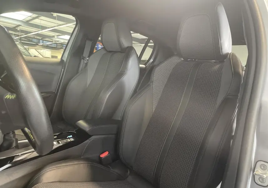 Gros plan sur les sièges avant en tissu et cuir noir de la Peugeot 208 gris clair métallisé, vue côté gauche intérieur.