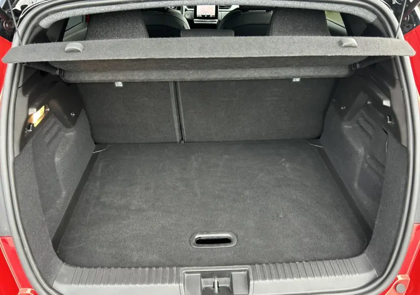 Vue arrière du coffre ouvert du Renault Captur 2025 Rouge Flamme avec intérieur noir et plancher plat.