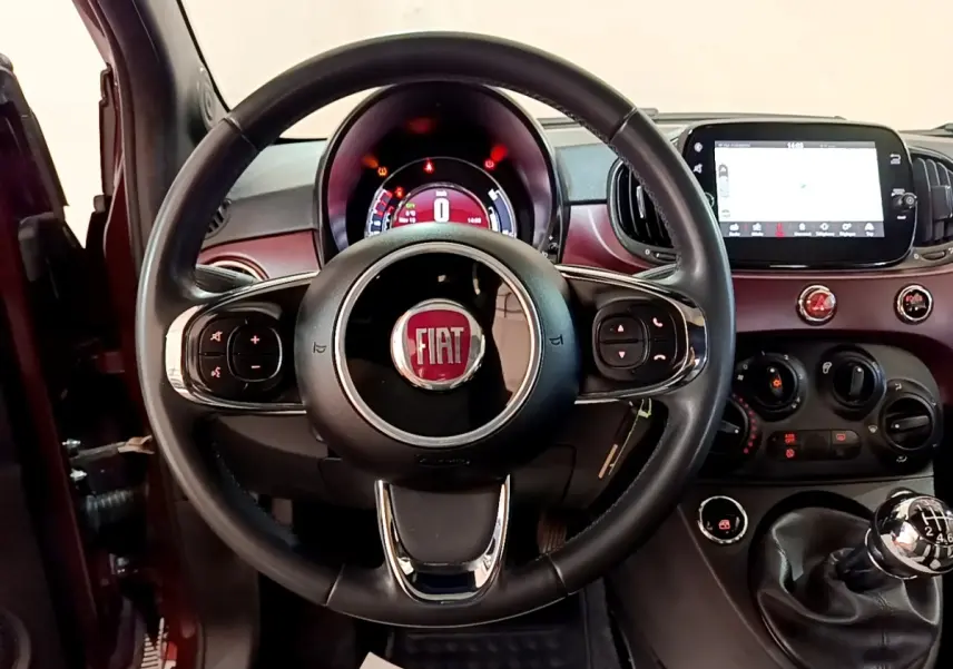 Vue intérieure centrée sur le volant cuir noir et tableau de bord rouge de la FIAT 500 1.0 70ch BSG Star 2021.