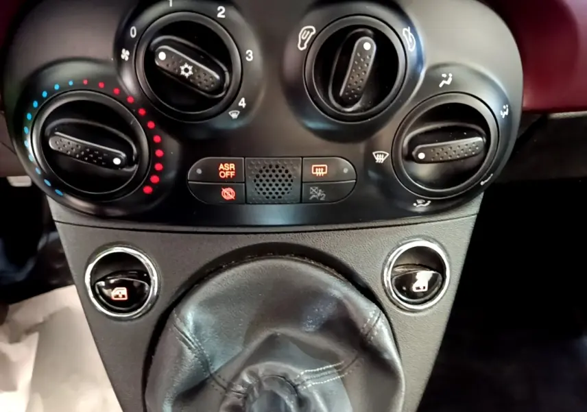 Gros plan sur les commandes de climatisation et le levier de vitesse cuir noir de la FIAT 500 rouge, version 1.0 70ch BSG Star.