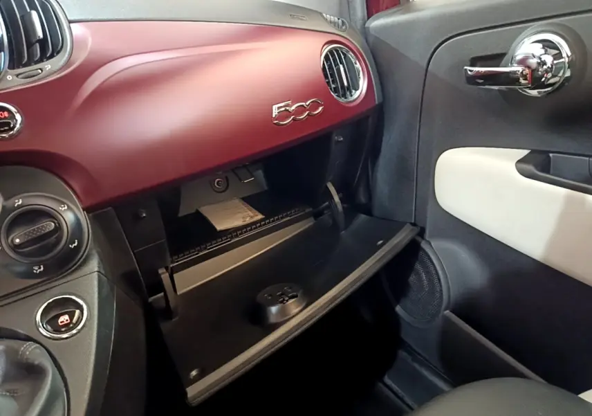 Vue intérieure côté passager du tableau de bord rouge mat et boîte à gants ouverte de la Fiat 500 1.0 70ch BSG Star.