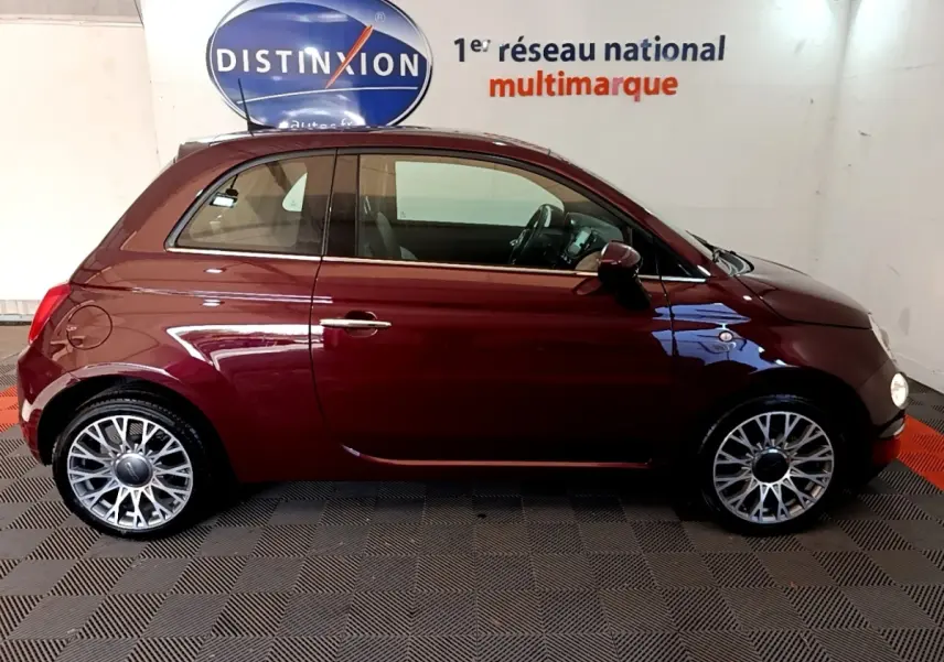 Profil droit d'une FIAT 500 rouge foncé 2021 avec jantes alliage et intérieur visible en arrière-plan.