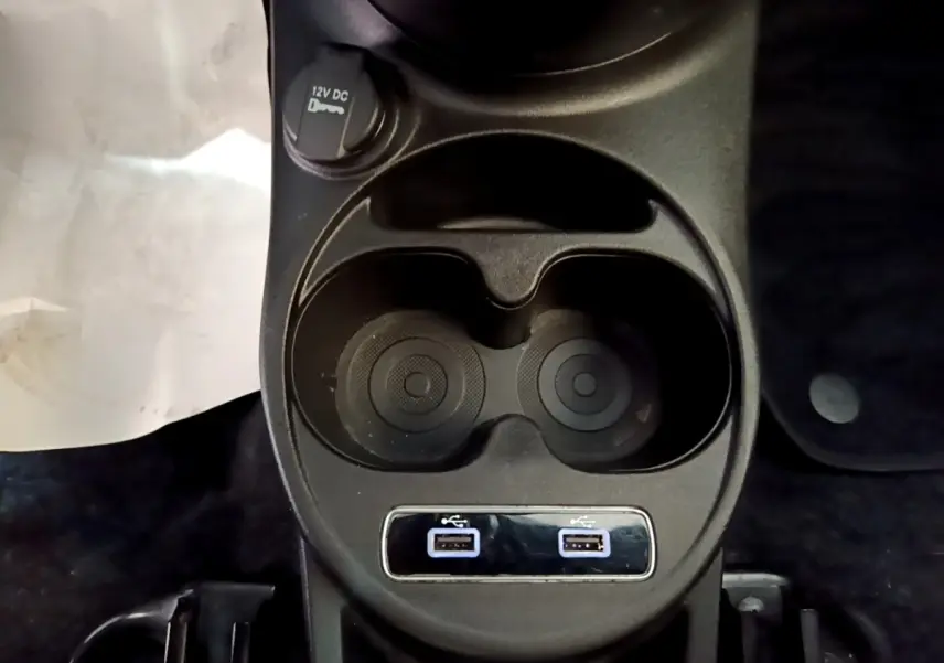 Vue rapprochée du porte-gobelets noir avec deux ports USB et prise 12V dans une FIAT 500 rouge.