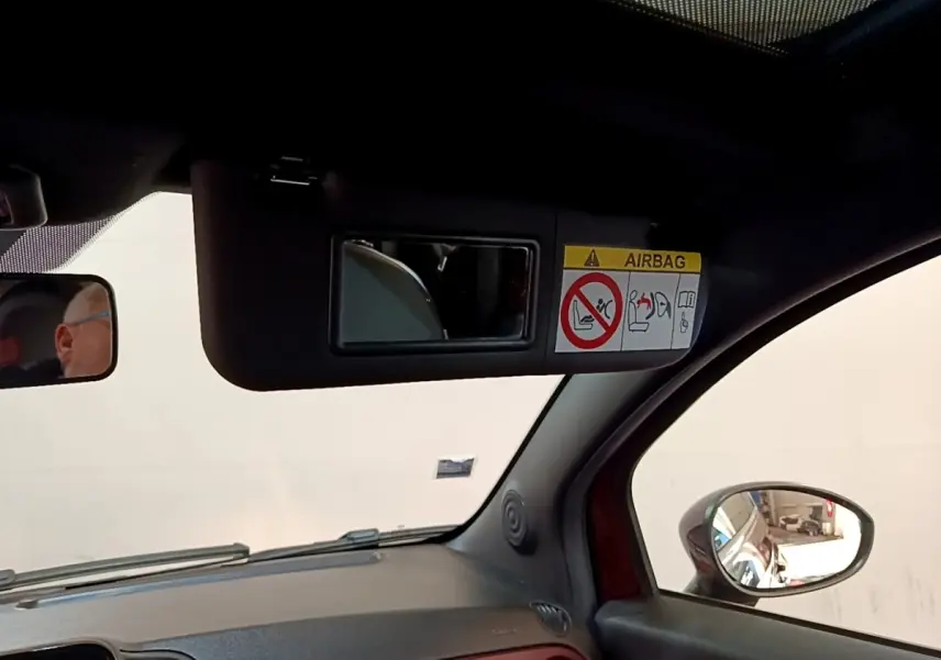 Vue intérieure côté passager de la FIAT 500 rouge, avec pare-soleil et miroir de courtoisie ouvert.